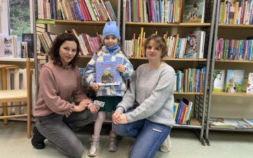 Dziewczynka i bibliotekarki prezentują książeczkę