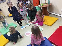 dzieci siedxą kolo bibliotrekarki podczas wspólnej zabawy