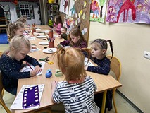 Dzieci siedzą przy stoliku i kolorują motyle