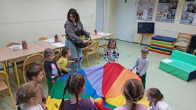 Bibliotekarka z dziećmi w trakcie zabawy chustą animacyjną