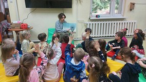 Bibliotekarka czyta dzieciom książkę i pokazuje obrazki