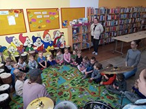 Dzieci siedzą na dywanie i słuchają opowieści