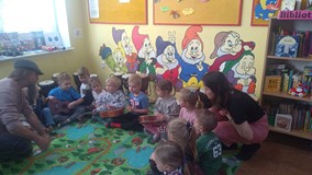 Dzieci siedzą na dywanie i graja na ukulele