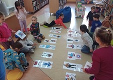 NUTKI z Przedszkola nr 15 siedzą na podłodze i dopasowują atrybuty do wizerunków superbohaterów