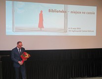 Bibliotekarz Roku Piotr Saporowski z kwiatami w Koszalińskiej Bibliotece Publicznej w Dniu Bibliotek