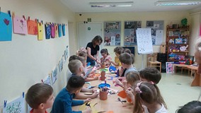 Bibliotekarka i dzieci przy pracy plastycznej