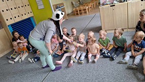 bibliotekarka rozdaje dzieciom książki