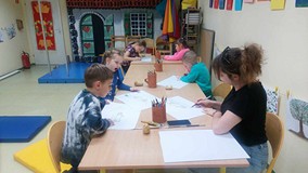 Bibliotekarka i dzieci przy pracy plastycznej