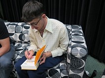 Grzegorz Piątek składa autograf w swojej książce.