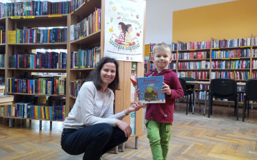 Chłopiec z bibliotekarką pokazują książkę i zakładkę