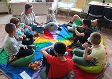 Dzieci rozmawiają z prowadzącą siedząc w kole