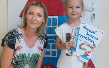 Zdjęcie dziewczynki z dyplomem i bibiotekarki