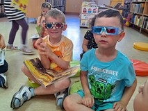 Na zdjęciu przedszkolaki przeglądają książki o dinozaurach