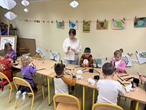 Bibliotekarka pomaga dzieciom przy pracy plastycznej