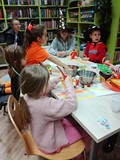 Dzieci podczas pracy nad dyniami z papieru w towarzystwie mam