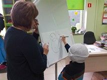 Chłopiec z zasłoniętymi oczami rysuje misia. Grupa Wiewiórek 27. listopada