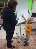 Chłopiec z zasłoniętymi oczami rysuje misia. Grupa Tygrysków