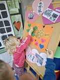 Dziewczynka przykleja serduszko na plakat
