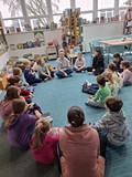 dzieci siedzą z prowadzącą w kręgu i rozmawiają o emocjach