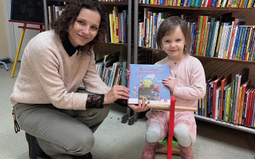 Dziewczynka z bibliotekarką prezentują książeczkę