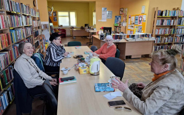 Cztery panie siedzą przy stole i dyskutują o książce