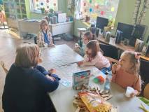 Uczestnicy spotkania i pani Ania grają w grę planszową
