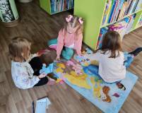 Trzy dziewczynki układają wielkie puzzle na podłodze