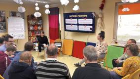 Uczestnicy siedzą na krzesłach i oglądają prezentację multimedialną