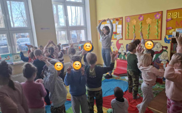 Dzieci wraz z bibliotekarką podczas zabawy z chustą animacyjną