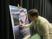 Sławomir Gortych podpisuje plakat w Koszalińskiej Bibliotece Publicznej