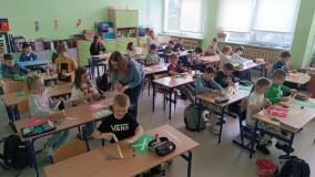 Uczniowie wyklejają pracę plastyczną