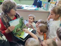 Pani Ania pokazuje dzieciom książkę o dinozaurach