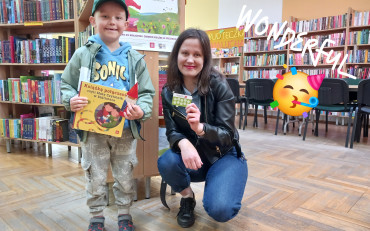 Bibliotekarka z chłopcem trzymają książkę i kartę biblioteczną