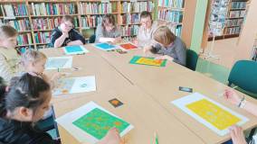 Uczestnicy wykonują laurki dla bibliotekarza