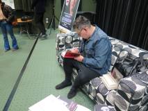 Michał Witkowski składający autograf w książce.