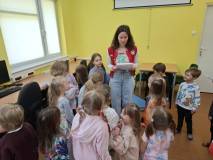 Bibliotekarka czyta dzieciom zadanie do wykonania