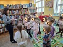 Dziesi stoją na dywanie, a bibliotekarka czyta dzieciom zagadkę