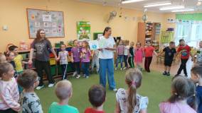 Dzieci chodzą w kole, bibliotekarka pokazuje książkę