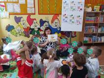 Bibliotekarka pokazuje dzieciom plansze edukacyjne.