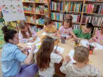 Dzieci siedzą przy stole wykonują pracę plastyczną