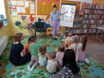 Bibliotekrka pokazuje dzieciom na tablicy obrazki owadów