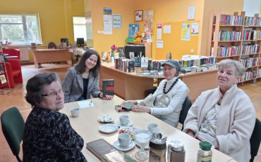 Panie siedzą przy stole i rozmawiają o książce