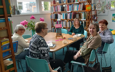 panie siedzą przy stole i dyskutują o przeczytanej książce z bibliotekarką