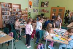 Bibliotekarka pomaga uczniom w wykonywaniu prac plastycznych