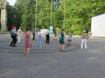 Uczestnicy wydarzenia tańczą na placu przed biblioteką.