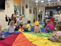 Dzieci słuchają jak bibliotekarka czyta im książkę