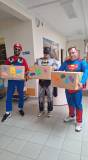 Batman, Superman i Mario pozują do zdjęcia z kartonami ksiażek od cytelników naszej biblioteki
