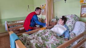 Superman trzyma za rękę pacjentkę hospicjum