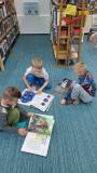 trzech chłopców oglądają książki w nasej bibliotece