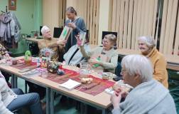 Bibliotekarka wręcza książkowe upominki, jedna z uczestniczek pokazuje jaką książkę otrzymała.  